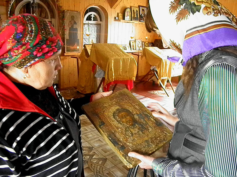 Старинные иконы, одну из которых прихожанка показывает заместителю председателя районного совета Татьяне Уткиной, нуждаются в реставрации