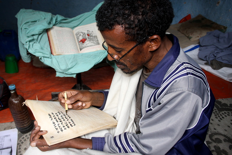 За перепиской сакрального манускрипта. Как и столетия назад, каллиграф использует пергамен и пишет на коленях. Монастырь Дебре-Либанос, Эфиопия. (Фото 2014 г.)